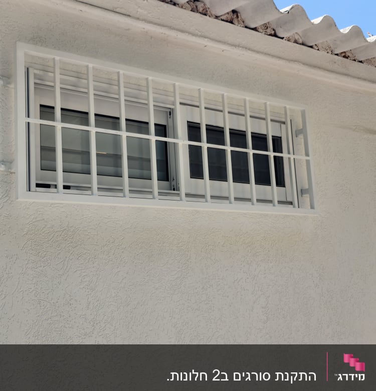 חלון עם סורגים על קיר חיצוני לבן